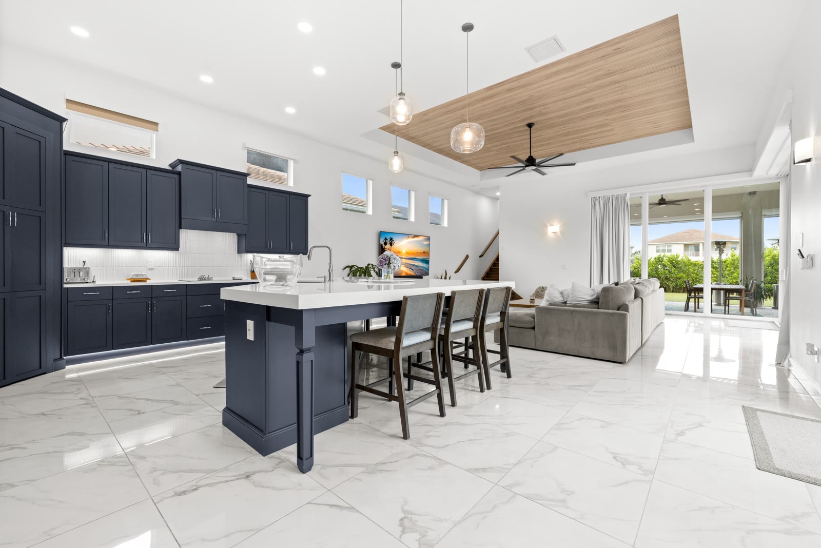 Open concept navy blue kitchen and living room with wood ceiling accent