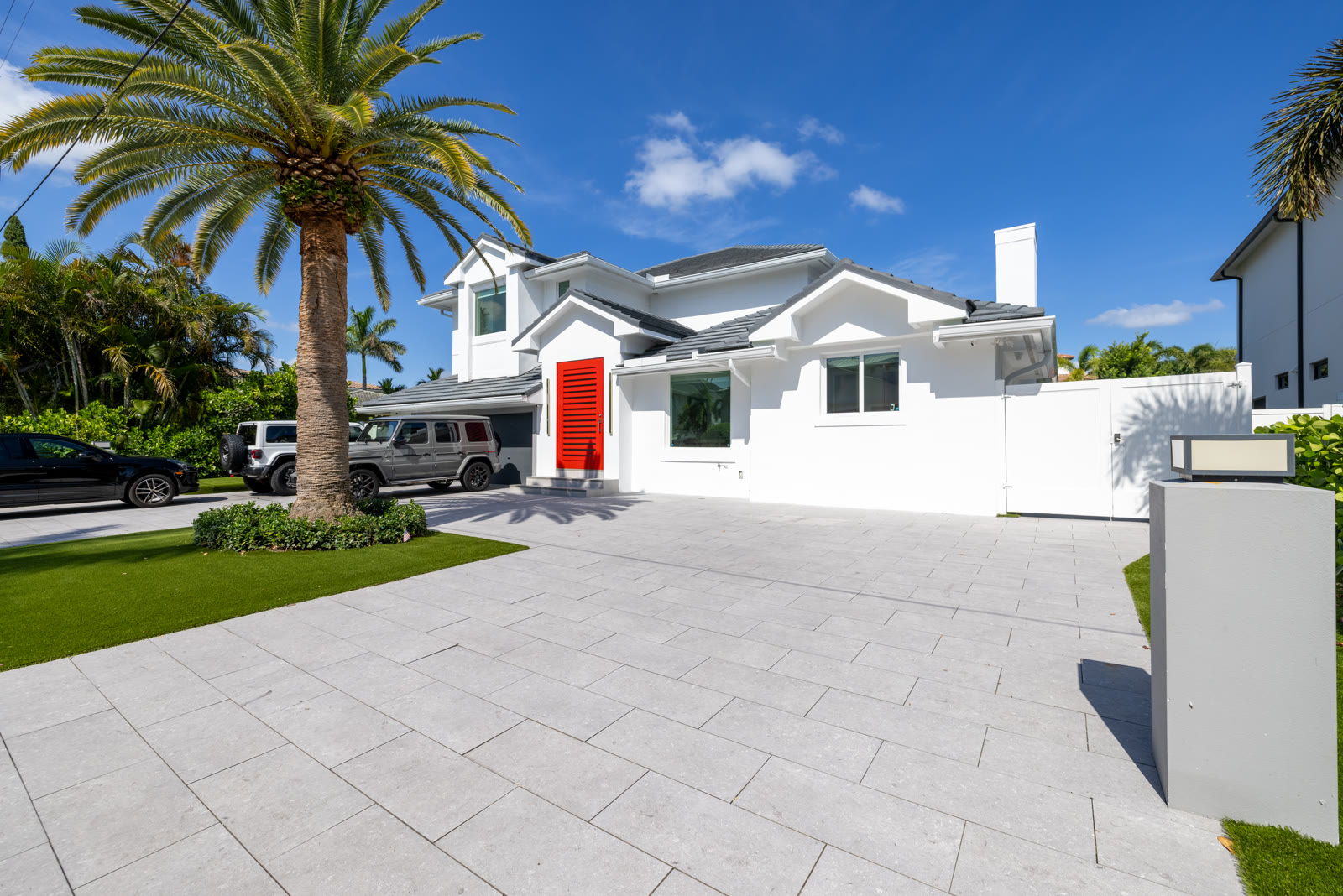 Front exterior of a modern home on Harbor Isle Dr. in Boca Raton with a red front door