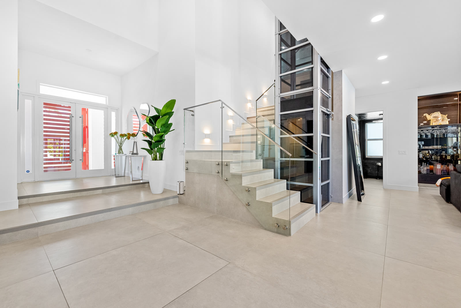Glass staircase and elevator in a modern Boca Raton home entryway