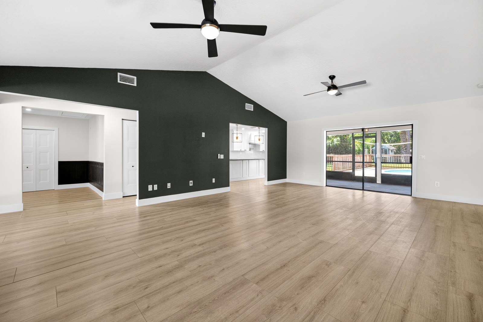 Unfurnished living room with vaulted ceiling and dark accent wall in Jupiter Farms, FL